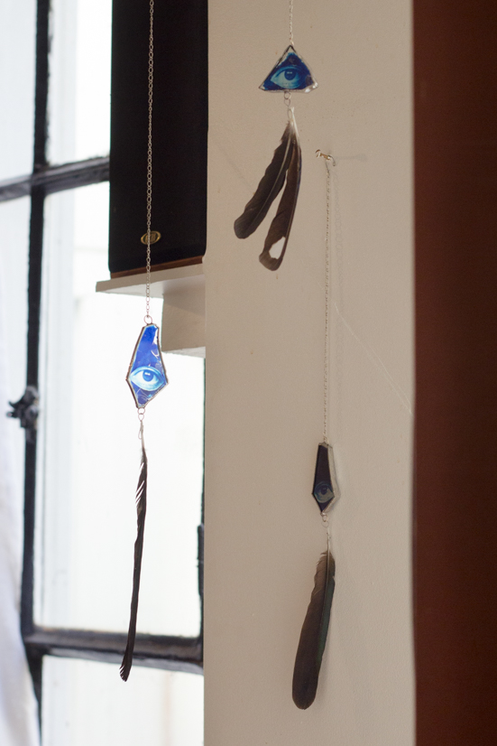 mobiles made with cyanotype prints of eyes on glass, and magpie / crows feathers